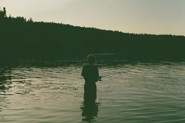 A person fishing waist-deep in a lake