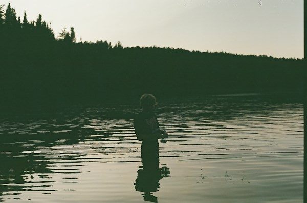 A person fishing in a lake at dusk