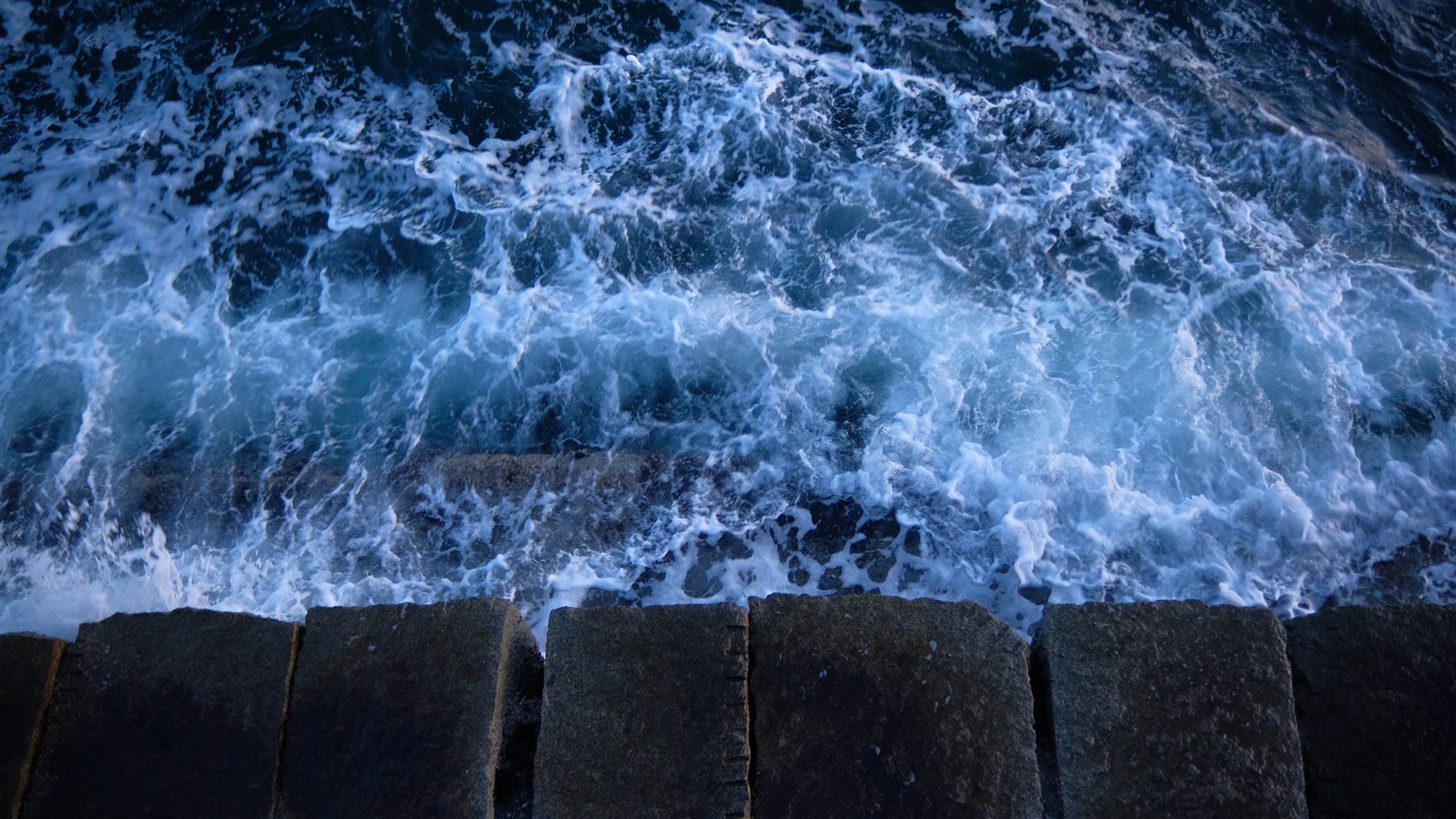 Waves crashing over dark rocks
