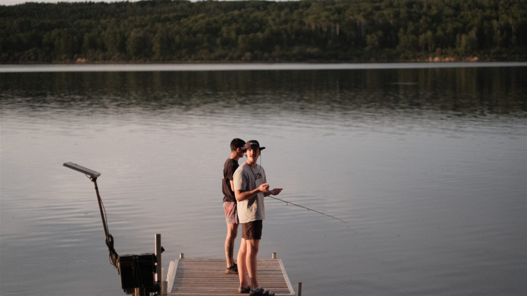 Two people fishing from a dock on a lake