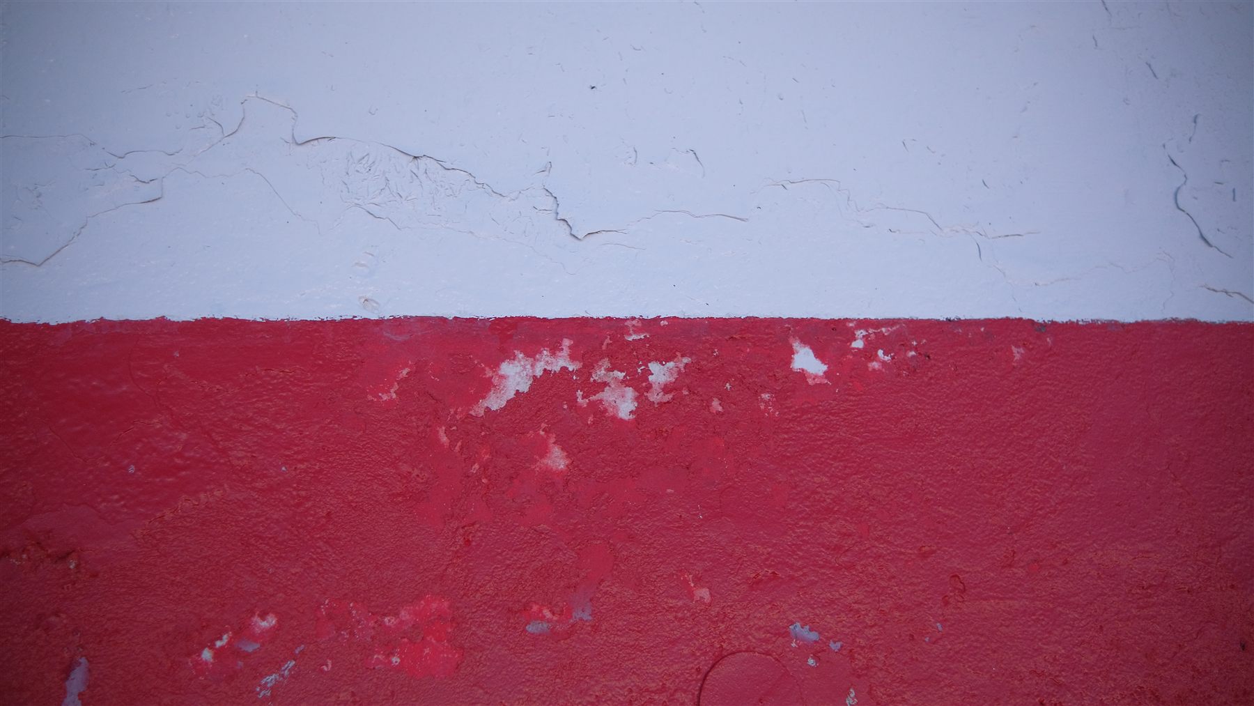 Cracked red paint on a white wall