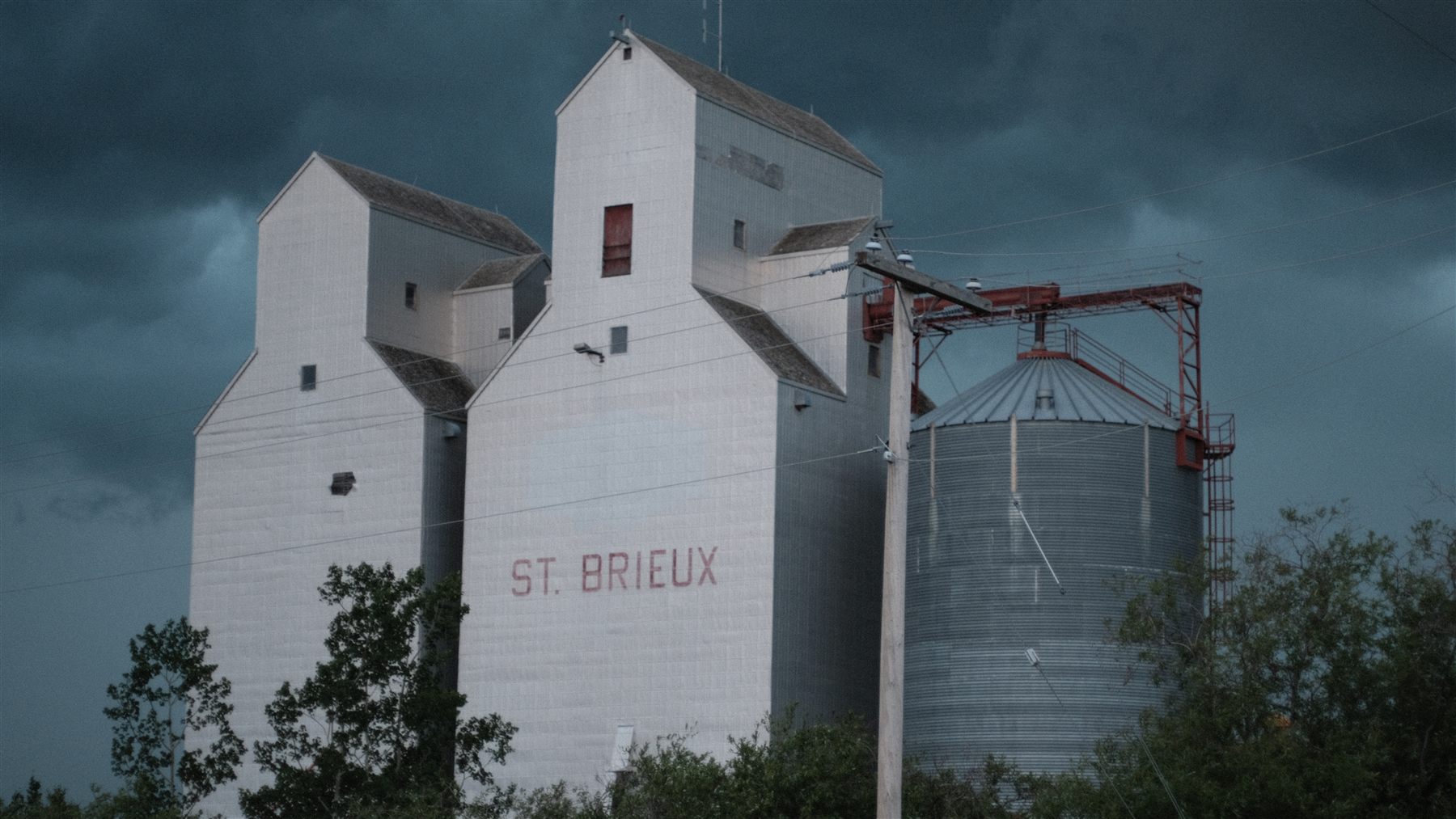 White grain elevators under a dark sky